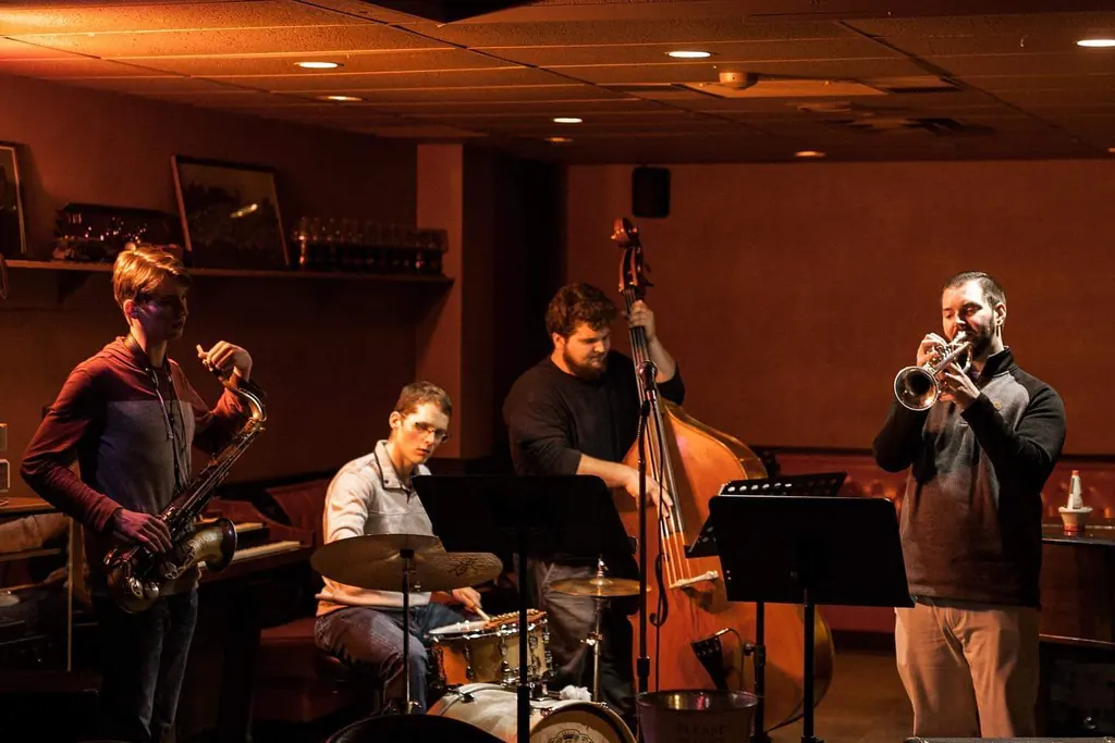 A jazz quartet mid-set in the corner of The Columbian, with saxophone, drums, upright bass and trumpet