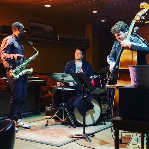 A saxophonist, drummer and upright bass player performing a set at The Columbian