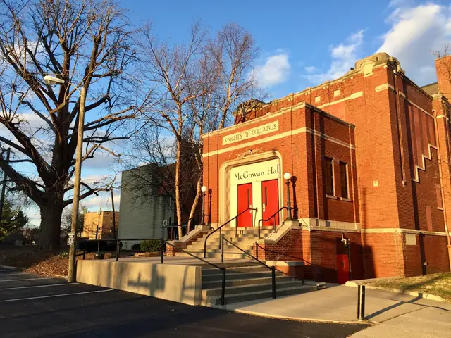 The red brick front of McGowan Hall on North Delaware Street, with red doors under carved stone lettering